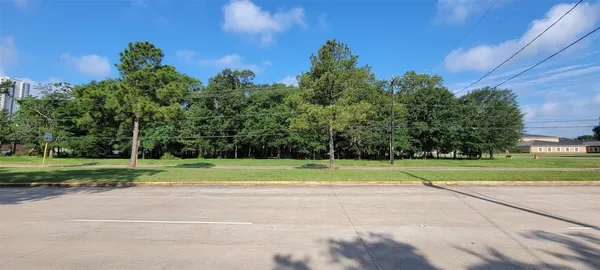 a green field with lots of trees in the background