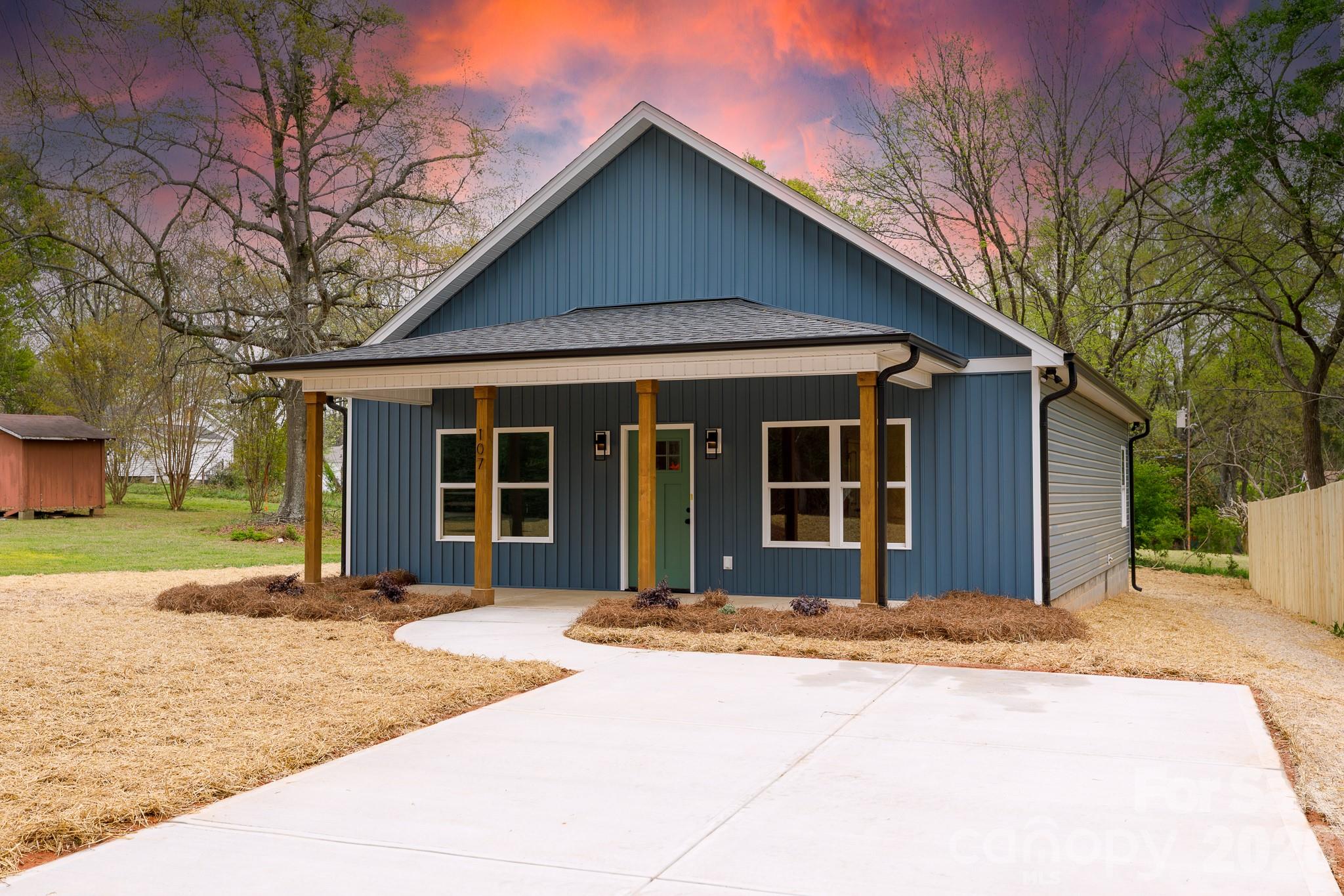 a front view of a house with a garden and trees