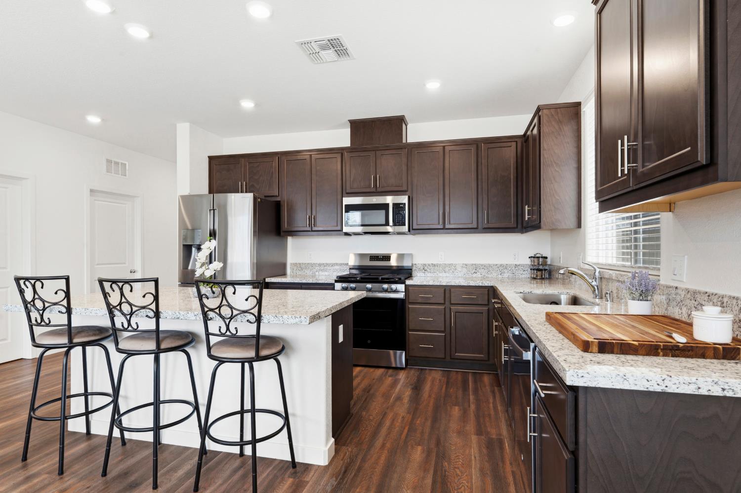 5713 Natalie Way Keyes, CA 95328 - Photo 4 of 30 a kitchen with stainless steel appliances granite countertop a stove top oven a sink dishwasher a refrigerator with a dining table and chairs