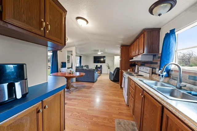 a kitchen with stainless steel appliances granite countertop a sink a stove and a wooden cabinets