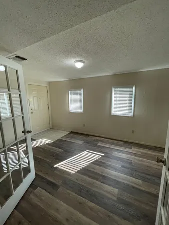 a view of an empty room with wooden floor and a window