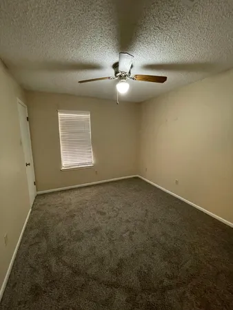 an empty room with a ceiling fan and window