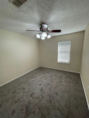 an empty room with a chandelier fan and windows