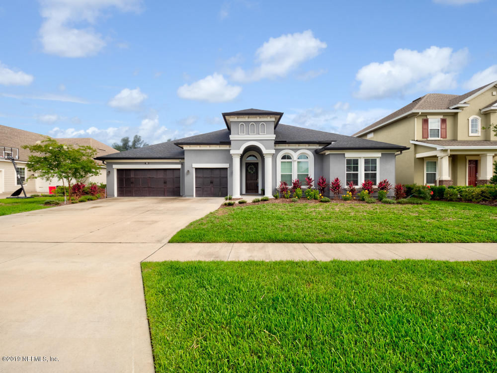 a front view of a house with a yard and potted plants