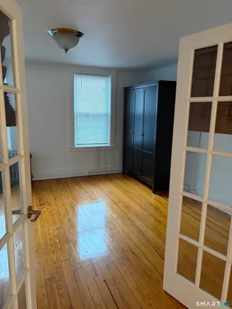 a view of empty room with wooden floor and fan