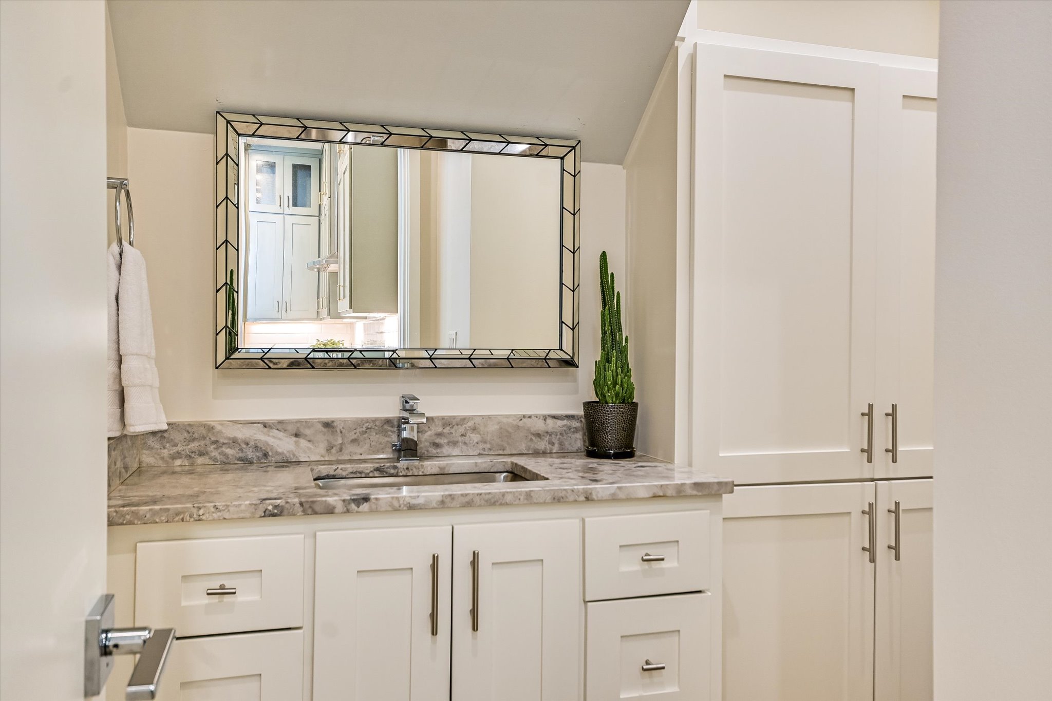 1605 Hether Street Austin, TX 78704 - Photo 14 of 26 White shaker cabinetry with brushed nickel hardware, undermount sink, stone countertop, and a decorative framed mirror