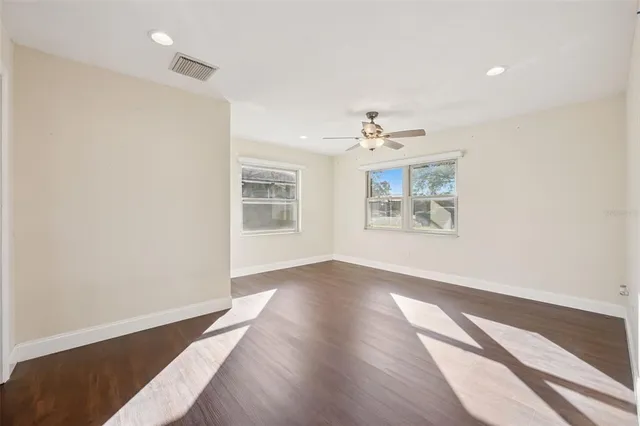 an empty room with wooden floor and windows