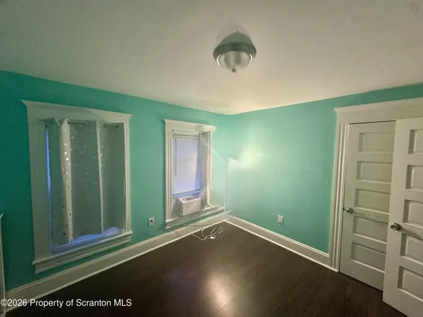 a view of an empty room with a window and wooden floor