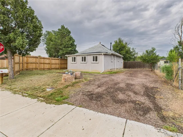 a backyard of house with large trees and wooden fence
