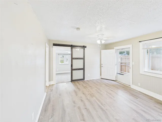 a view of an empty room with window and wooden floor