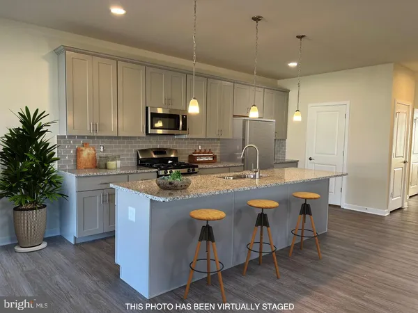 a view of a kitchen counter space with wooden floor and white cabinets