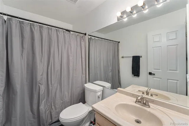 a bathroom with a sink a toilet a mirror and shower curtain