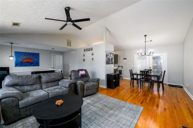 a living room with furniture and a dining table with wooden floor