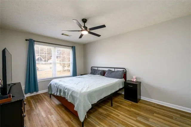a bedroom with a large bed and a flat tv screen on dresser