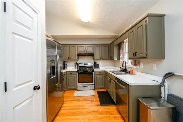 a kitchen with a sink a stove wooden cabinetry and stainless steel appliances