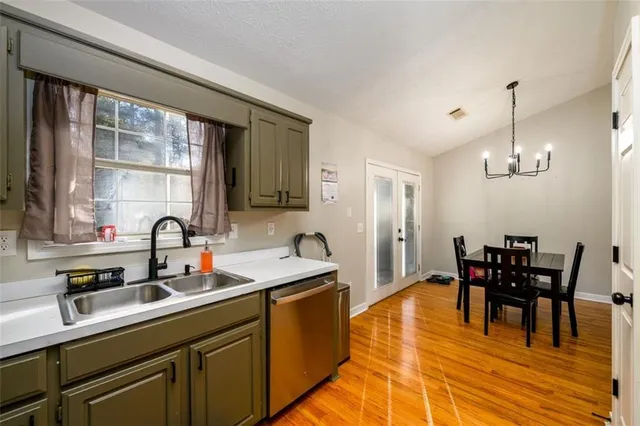 a kitchen with stainless steel appliances granite countertop a sink dishwasher a dining table and chairs with wooden floor