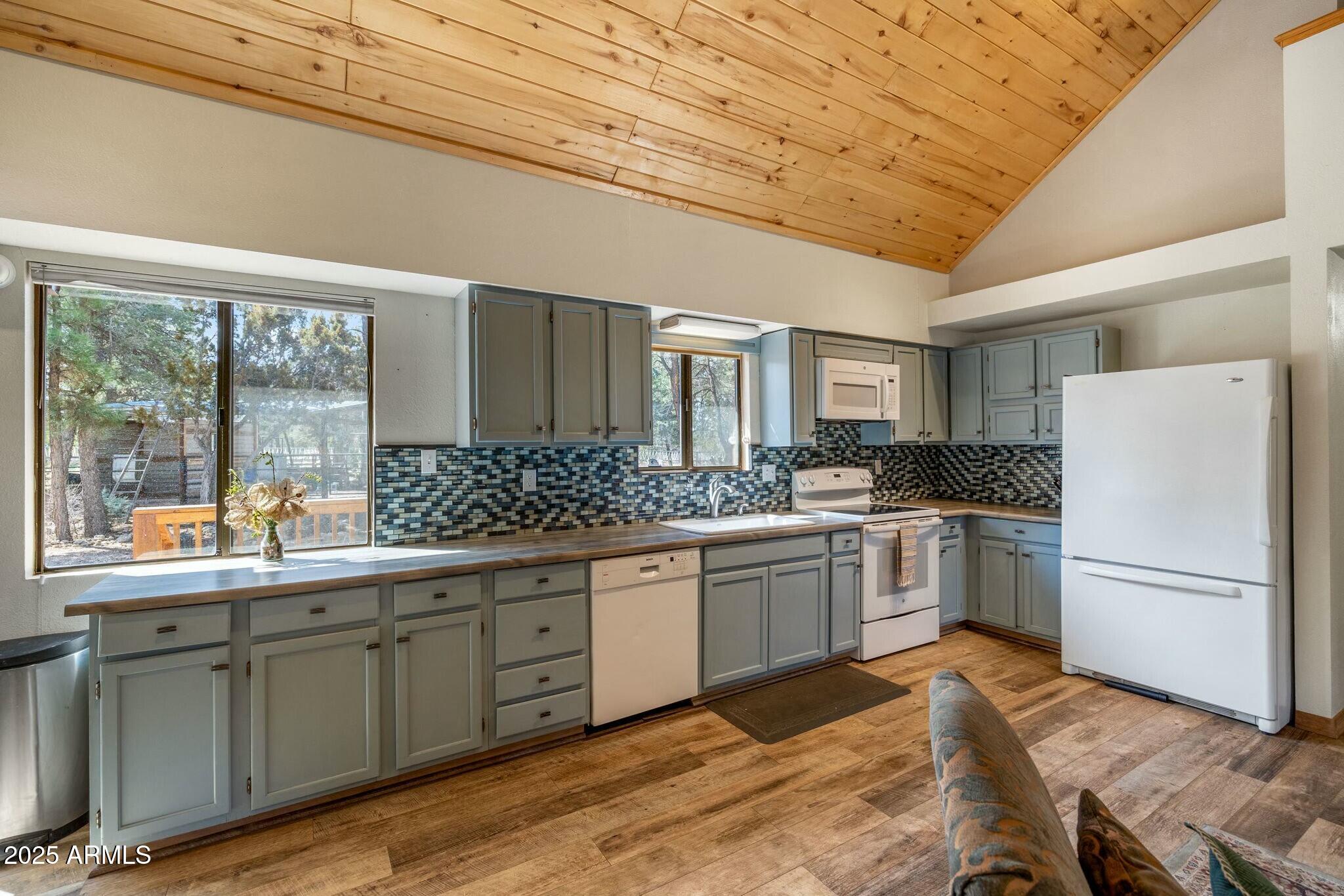 2061 Cherokee Strip Road Overgaard, AZ 85933 - Photo 11 of 40 a kitchen with stainless steel appliances granite countertop a refrigerator a sink dishwasher a stove and white countertops with wooden floor