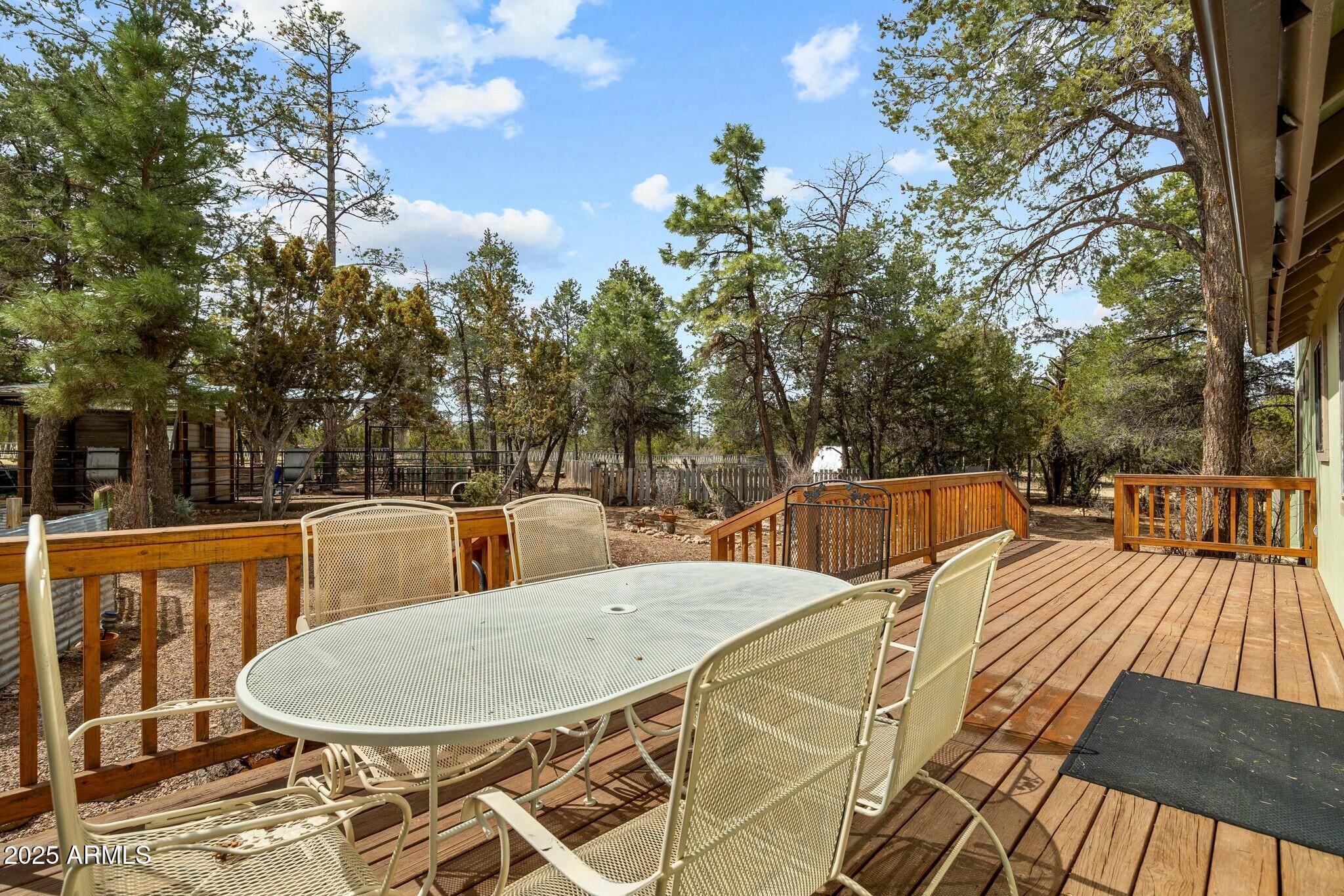 2061 Cherokee Strip Road Overgaard, AZ 85933 - Photo 30 of 40 a view of a patio with table and chairs with wooden floor and fence