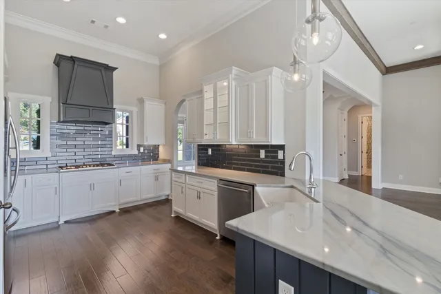 a kitchen with a sink dishwasher a stove and white cabinets with wooden floor
