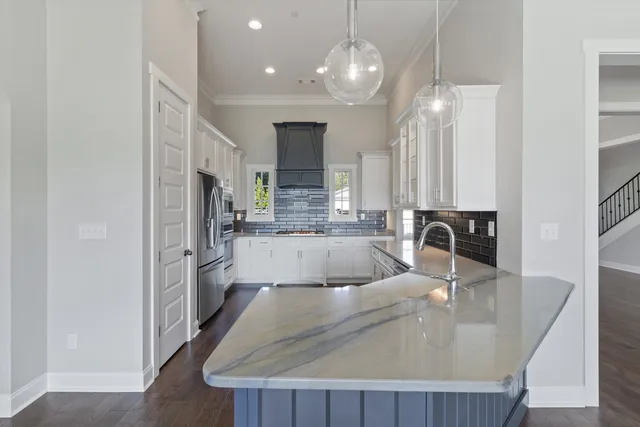 a large kitchen with granite countertop a sink a counter top appliances and cabinets