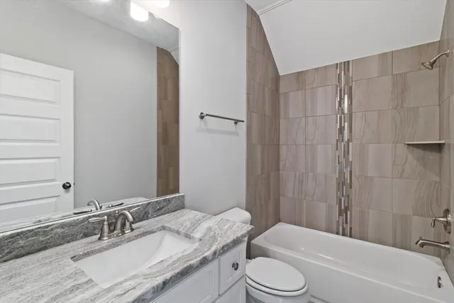 a bathroom with a granite countertop sink toilet a mirror a bathtub and shower
