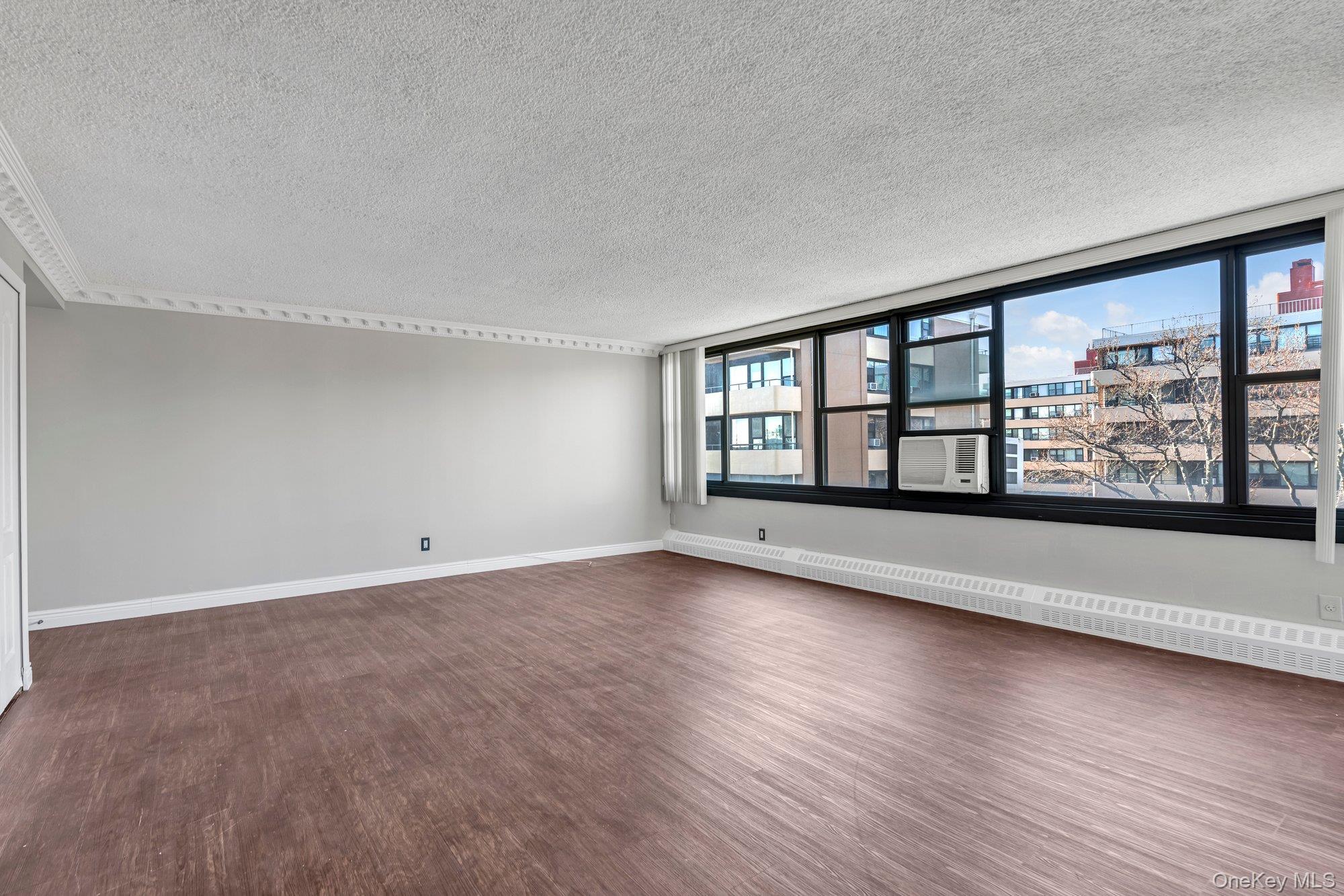 168-01 12th Avenue, Unit 7B Queens, NY 11357 - Photo 3 of 12 a view of an empty room with a window and wooden floor