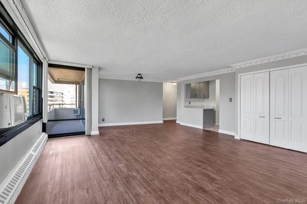 a view of an empty room with a window and wooden floor