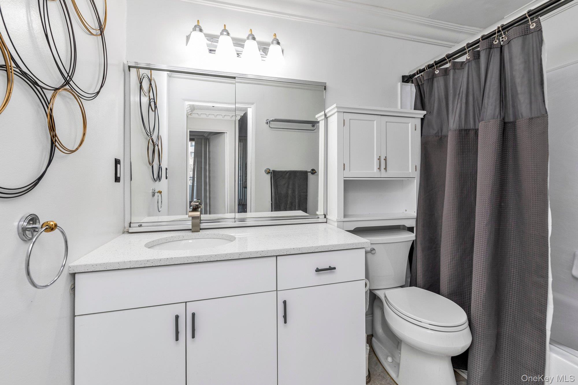 168-01 12th Avenue, Unit 7B Queens, NY 11357 - Photo 7 of 12 a bathroom with a sink vanity mirror and toilet