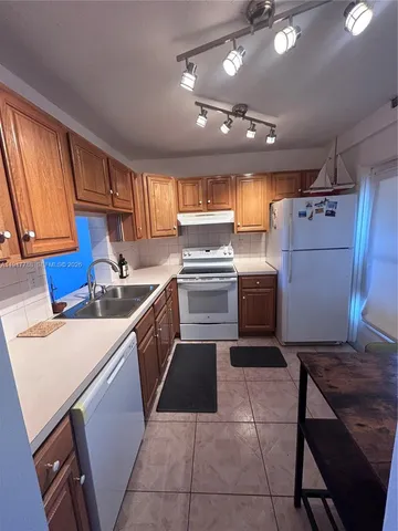 a kitchen with a sink a refrigerator and cabinets