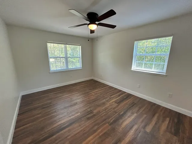 a view of an empty room with wooden floor and a window