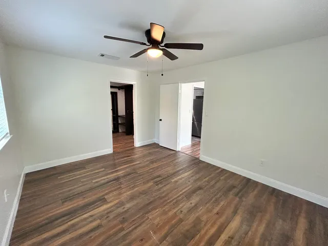 an empty room with wooden floor and ceiling fan