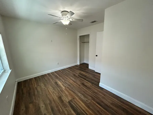a view of a room with wooden floor and a ceiling fan