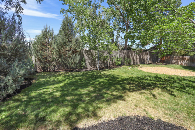 8938 Manchester Lane Sandy, UT 84093 - Photo 40 of 50 Spacious backyard featuring a wood fence, mature trees, and a combination of grass and bark mulch ground cover