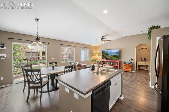 a kitchen with stainless steel appliances granite countertop a table chairs and a refrigerator
