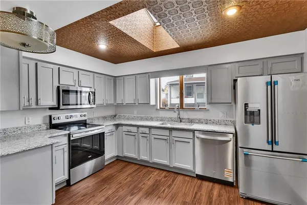 a kitchen with stainless steel appliances granite countertop a stove top oven a sink and dishwasher a refrigerator with wooden floor