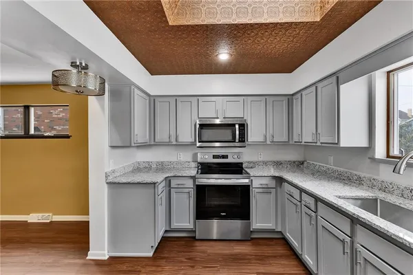 a kitchen with stainless steel appliances granite countertop a stove a sink and a microwave