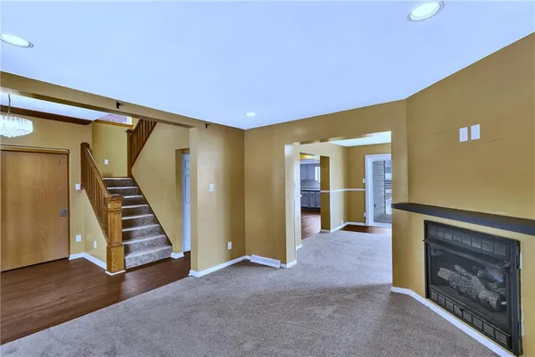 a view of an empty room with stairs and fire place
