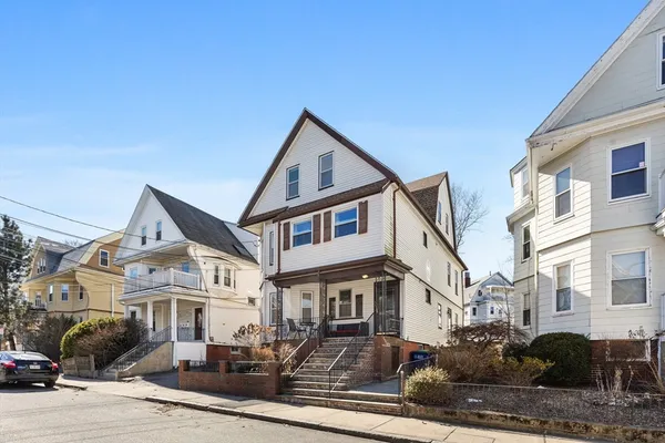 a view of a white house with large windows next to a road