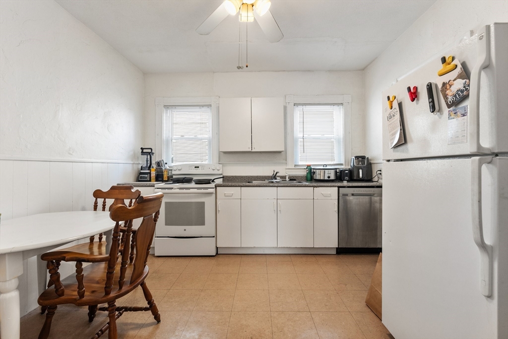 28 Pearson Road, Unit 1 Somerville, MA 02144 - Photo 3 of 18 a white kitchen with a refrigerator a stove a dining table and chairs