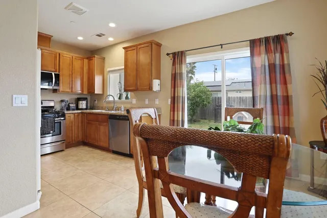 a living room with stainless steel appliances furniture a large window and a kitchen view