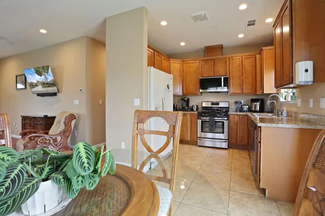 a kitchen with stainless steel appliances granite countertop a stove a sink a microwave a dining table and chairs