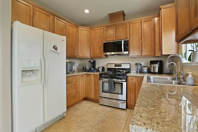 a kitchen with stainless steel appliances granite countertop a refrigerator stove a sink and a microwave