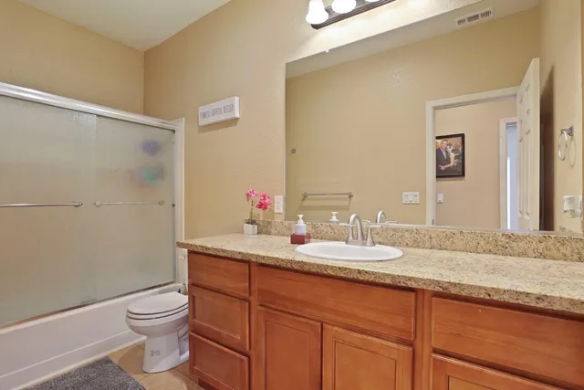 a bathroom with a granite countertop sink a toilet and a mirror