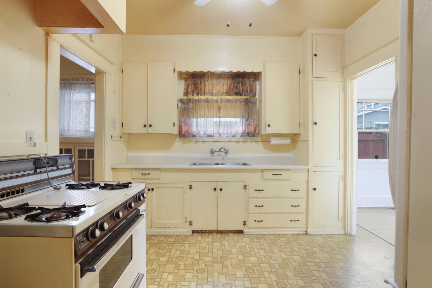 1428 West Harding Way Stockton, CA 95203 - Photo 13 of 32 a kitchen with granite countertop a stove sink and cabinets