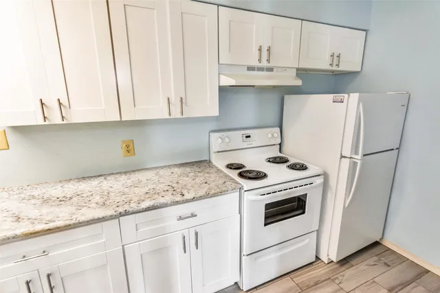 a kitchen with granite countertop white cabinets and refrigerator