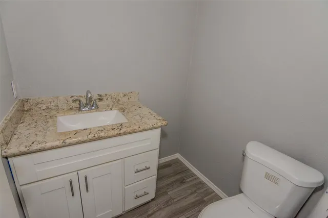 a bathroom with a granite countertop toilet and a sink