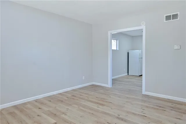 a view of an empty room with wooden floor and a mirror