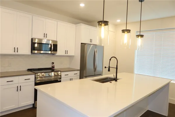 a kitchen with stainless steel appliances a stove a sink a refrigerator a counter space and cabinets