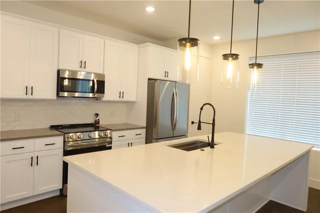 a kitchen with stainless steel appliances a stove a sink a refrigerator a counter space and cabinets