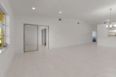 an empty room with chandelier fan and windows